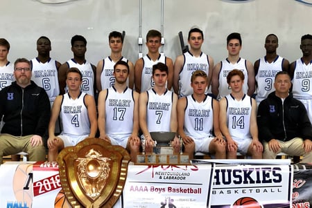 El equipo de baloncesto de la Holy Heart of Mary High School posó con un trofeo frente a la cancha de baloncesto.