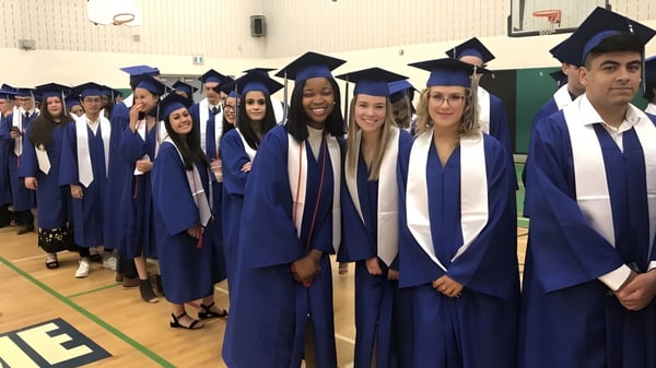 Un grupo de graduados está en togas azules en el auditorio de la Holy Trinity Catholic High School.