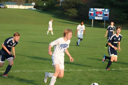 Estudiantes de la Houghton Academy juegan al fútbol en el campo durante un partido.