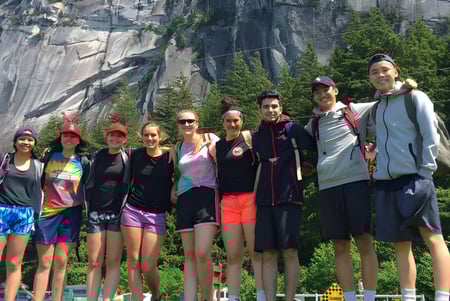 Un grupo de estudiantes de la Hugh Boyd Secondary School posan frente a una formación rocosa en el bosque.