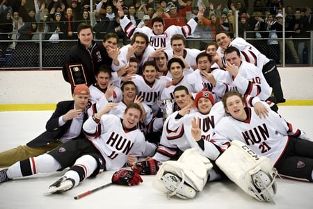 Un grupo de jugadores de hockey de The Hun School of Princeton posan para una foto de equipo sobre el hielo.