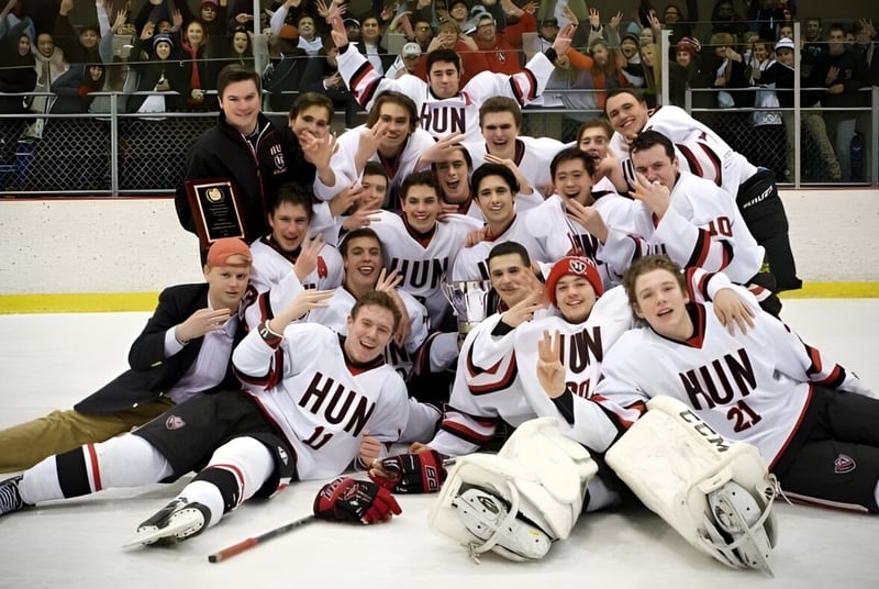 Un grupo de jugadores de hockey de The Hun School of Princeton posan para una foto de equipo sobre el hielo.