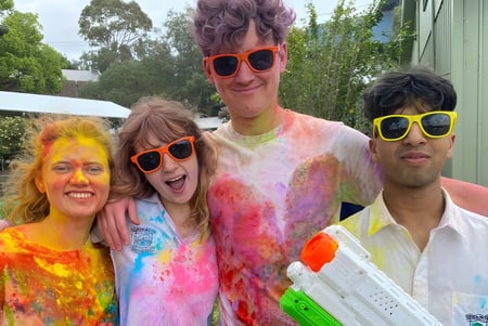 Estudiantes de la Hunters Hill High School celebran juntos al aire libre rodeados de vegetación verde.