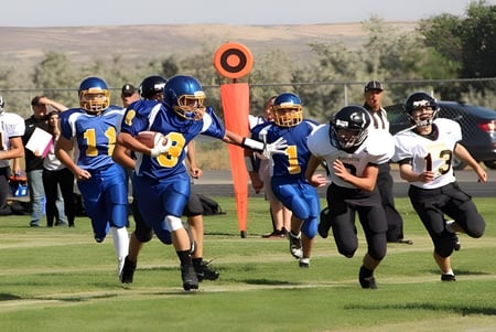 Un grupo de futbolistas entrena en el campo deportivo de Huntington High School frente a un paisaje montañoso.