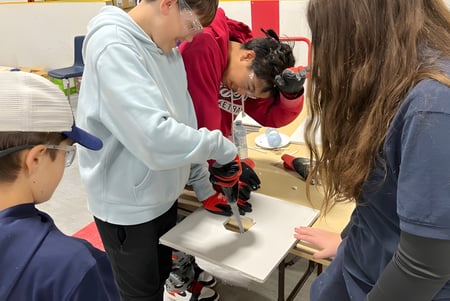 Estudiantes y docente en el aula del Huron-Perth Catholic District School Board con materiales de aprendizaje en el fondo.