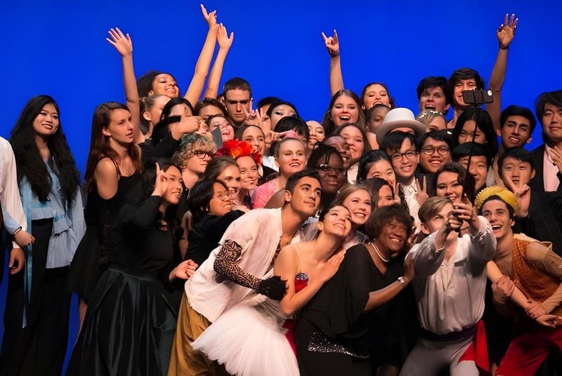 Estudiantes de la Idyllwild Arts Academy celebran juntos frente a un fondo azul.
