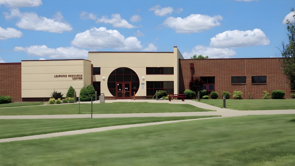 El moderno edificio de ladrillo de Illinois Eastern Community Colleges con una entrada de arco en un césped cuidado y rodeado de vegetación verde.