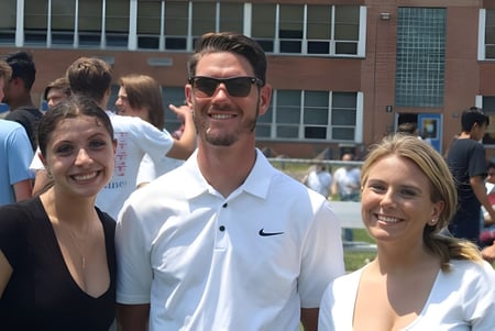 Tres estudiantes están juntos al aire libre en el campus de la Immaculata High School con un edificio de fondo.