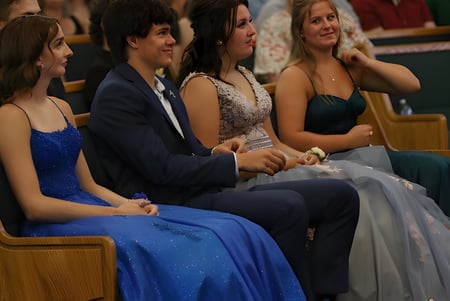 Un grupo de personas vestidas formalmente está sentado en un evento de la Immanuel Christian Secondary School en un teatro.