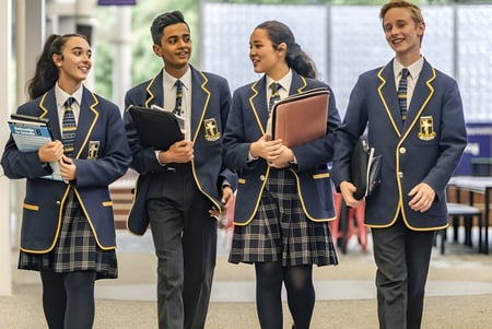 Un grupo de estudiantes en uniformes escolares está en el pasillo del Immanuel College.