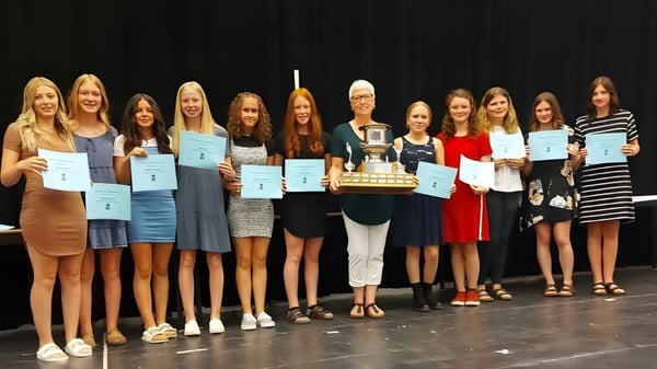 Estudiantes de Indian River High están juntos en el escenario sosteniendo certificados y un trofeo.