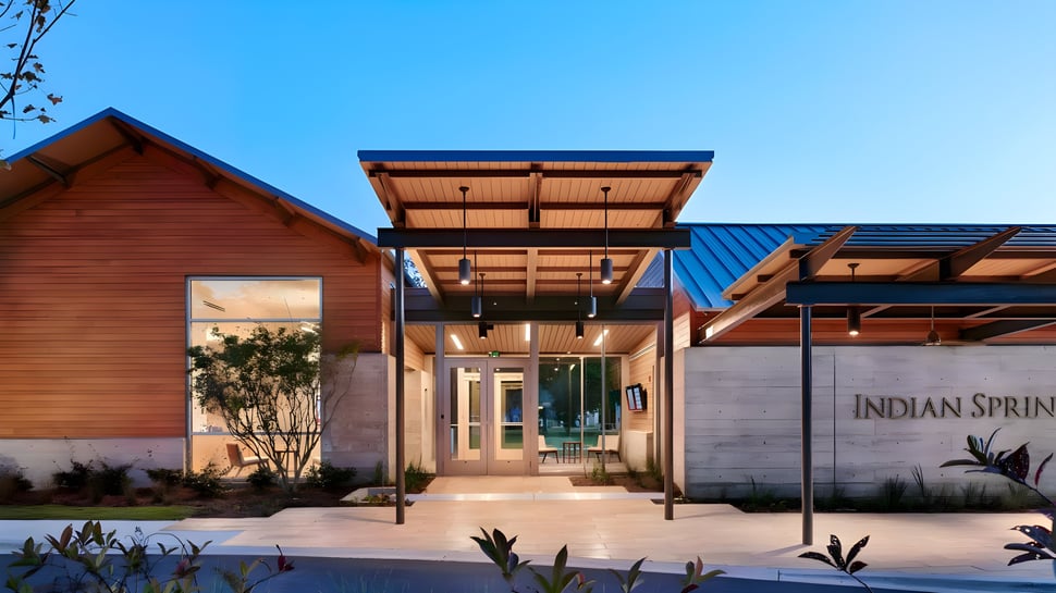 El moderno edificio de madera de la Indian Springs School con una entrada cubierta frente a un cielo despejado.
