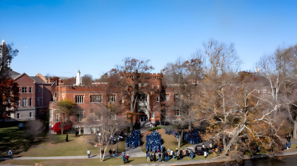 El edificio histórico similar a un castillo de la Indiana Private Highschool se ve frente a un cielo azul con árboles sin hojas y personas en el camino.