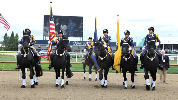 Un grupo de jinetes en uniforme sobre caballos negros con banderas está en la pista de carreras de la Indiana Private Highschool.