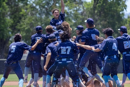 Estudiantes de la Indooroopilly State High School celebran juntos en el campo de béisbol al aire libre.