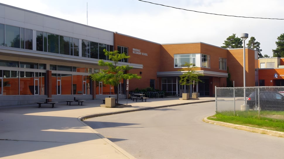 El moderno edificio de varios pisos de la Innisdale Secondary School con paredes de vidrio y elementos de fachada naranjas y grises.