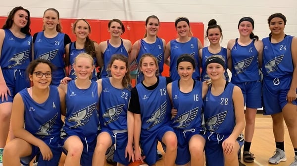 Un grupo de estudiantes de la Innisdale Secondary School en uniformes azules posan juntas en un gimnasio.