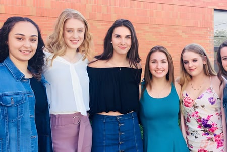 Un grupo de seis jóvenes estudiantes se encuentra frente a una pared de ladrillos en el terreno de la Innisdale Secondary School.