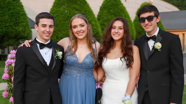 Cuatro personas bien vestidas posan juntas frente a un fondo verde en el terreno de la Ipswich School.