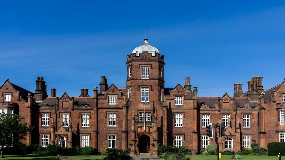 El edificio histórico de ladrillo con torre en el terreno de la Ipswich School se encuentra bajo un cielo azul claro.