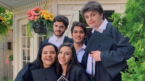 Un grupo de estudiantes de la Iroquois Ridge High School está de pie con ropa formal en un jardín con flores y áreas verdes.