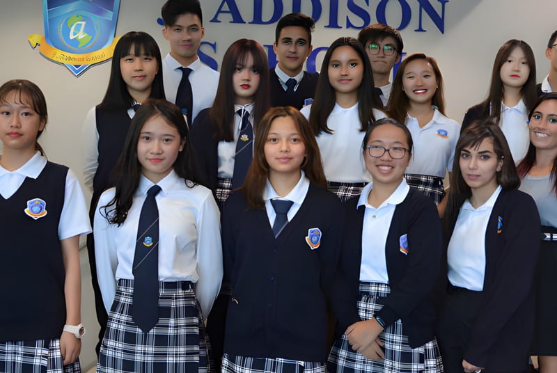 Un grupo de estudiantes de la J. Addison School posa frente a un fondo con el nombre y el logo de la escuela.