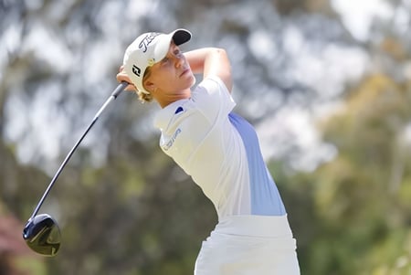 Un estudiante de la James Nash State High School golpea una pelota de golf en el campo de golf verde.