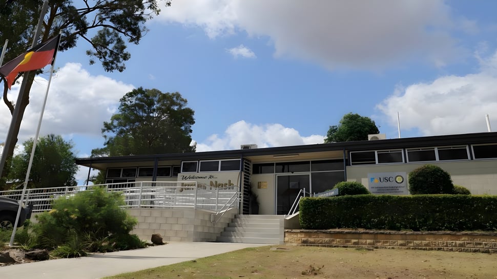 El moderno edificio de dos pisos de la James Nash State High School con grandes ventanas y entrada ajardinada.