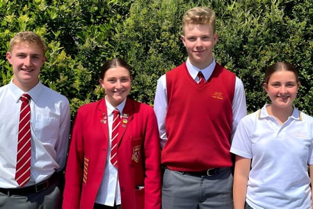 Cuatro estudiantes están de pie en una pradera verde en el campus del James Hargest College.