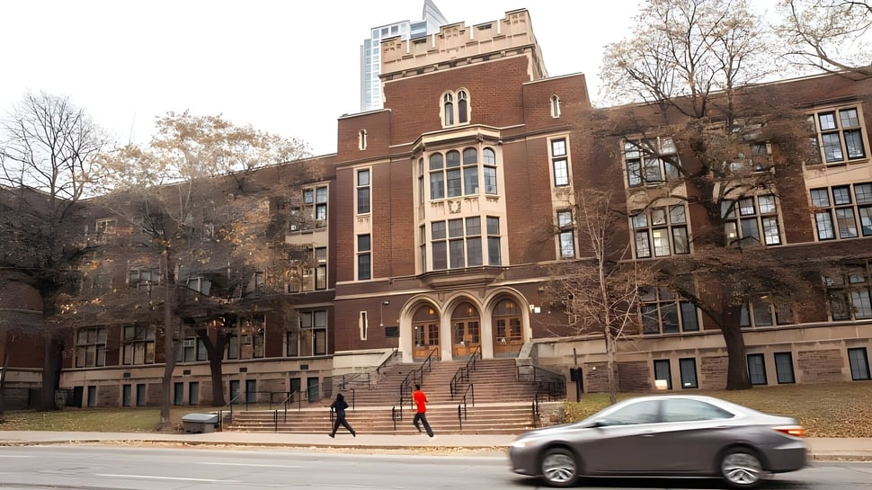El gran edificio de ladrillo con una torre prominente pertenece al Jarvis Collegiate Institute y está rodeado de árboles.
