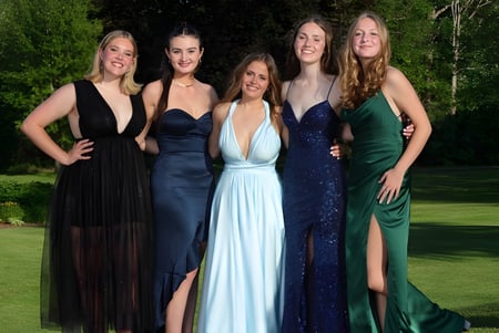 Un grupo de cinco estudiantes del John Abbott College posan en vestidos de noche formales en un área verde.