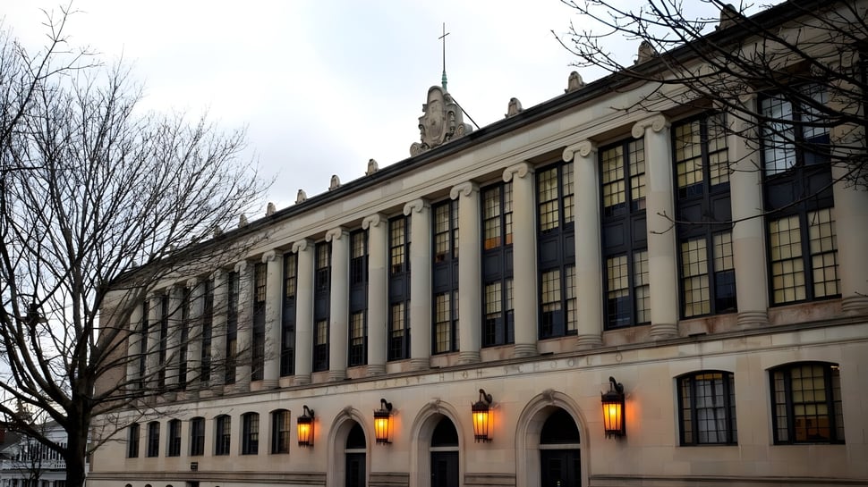 El magnífico edificio con ventanas de arco en el terreno de la John Bapst Memorial High School está rodeado de árboles desnudos.