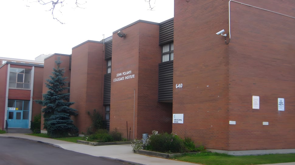 El edificio de ladrillo de varios pisos con un árbol y una zona verde en el terreno del John Polanyi Collegiate Institute.