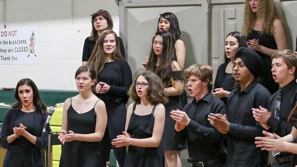 Un grupo de estudiantes está en una sala con un cartel en la pared en el campus del John Taylor Collegiate.
