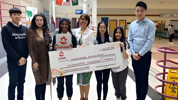 Estudiantes de la Johnston Heights Secondary School presentan un gran cheque en una entrega de donaciones.