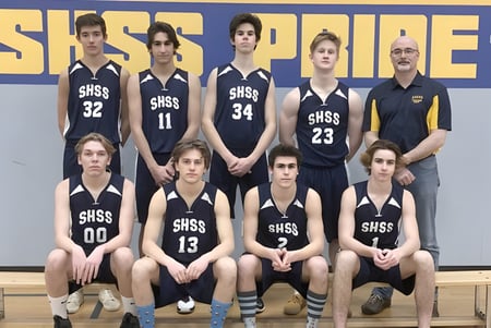 Estudiantes de la J.V. Humphries Secondary School posan juntos en sus camisetas de baloncesto frente a un fondo azul y amarillo.