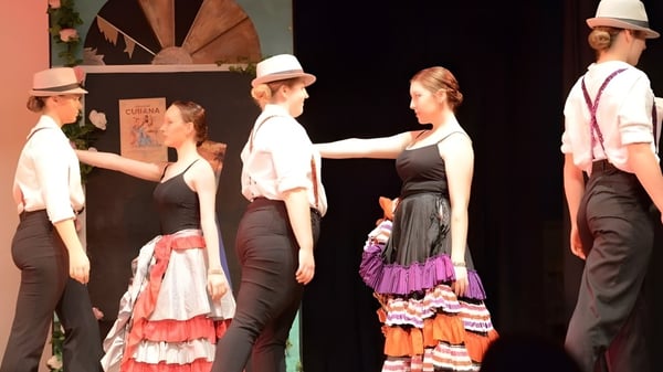 Estudiantes de la Kaiapoi High School en trajes tradicionales españoles durante una actuación de baile en el escenario.