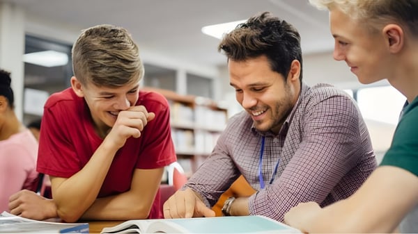 Tres estudiantes de la Kamloops School of the Arts están sentados juntos en la mesa y discuten en un entorno de aprendizaje.