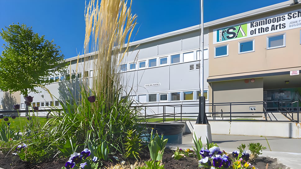 El moderno edificio escolar de la Kamloops School of the Arts está rodeado de plantas y flores.