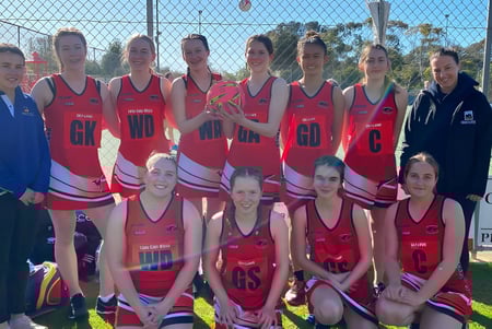 Un grupo de jóvenes atletas en uniformes rojos y blancos en el campo de deportes de la Kangaroo Island Community Education.