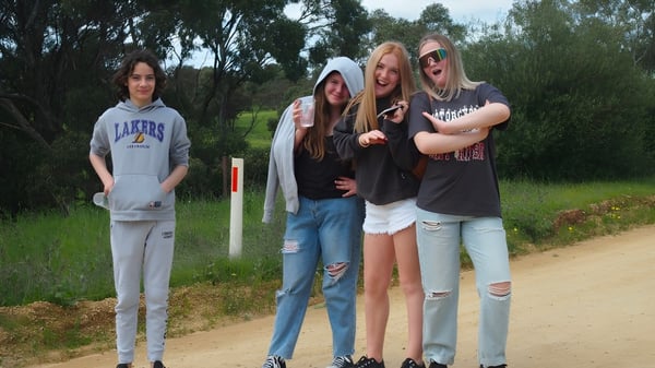 Cuatro estudiantes se agrupan en un entorno natural con árboles en el terreno de la Kapunda High School.