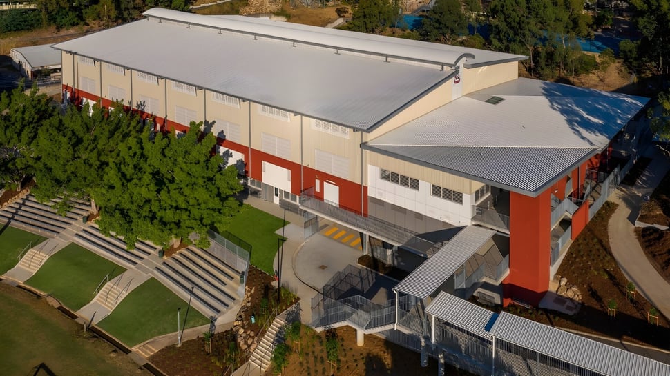 El moderno edificio industrial del Kelvin Grove State College se encuentra en una colina cubierta de hierba con vegetación circundante y cielo azul.