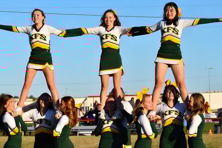 Los estudiantes de la Kenston Forest School realizan una acrobacia de animación en el campo deportivo bajo un cielo despejado.