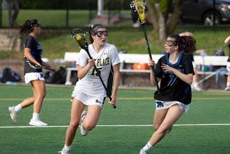 Dos jugadoras de la Kent Place School compiten en el campo en un partido de lacrosse.