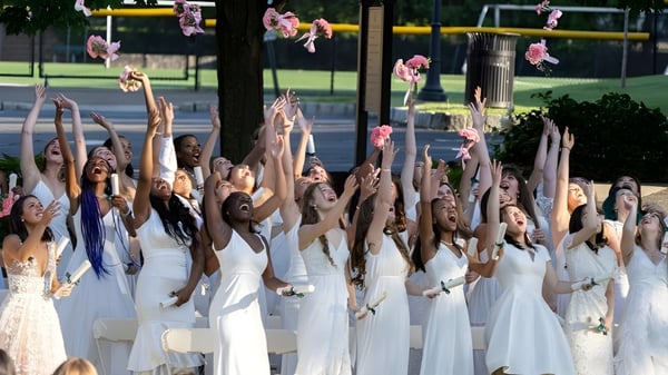 Un grupo de alumnas de la Kent Place School realiza una presentación de danza sincronizada al aire libre con un fondo verde.
