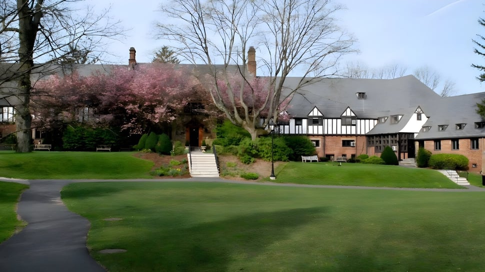 El edificio Tudor de la Kent Place School está rodeado de árboles en flor y un césped bien cuidado.