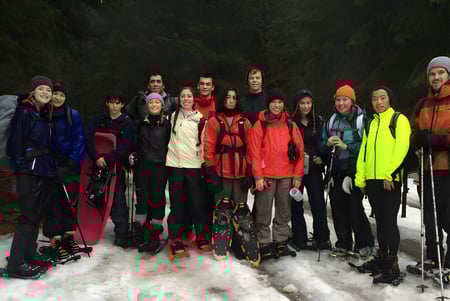 Un grupo de estudiantes de la Keystone School está de pie con colorida ropa de invierno en un bosque nevado.