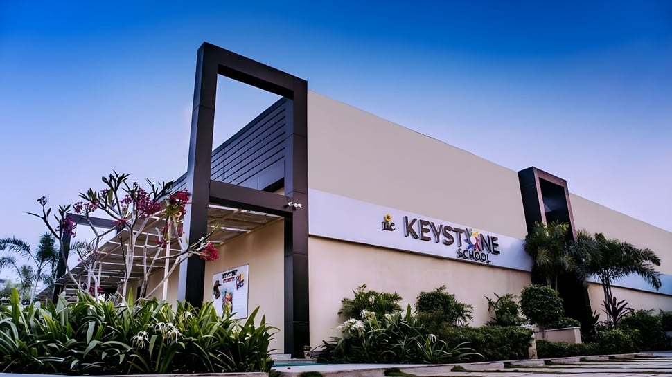 El moderno edificio de la Keystone School se ve frente a un cielo azul y rodeado de vegetación verde.