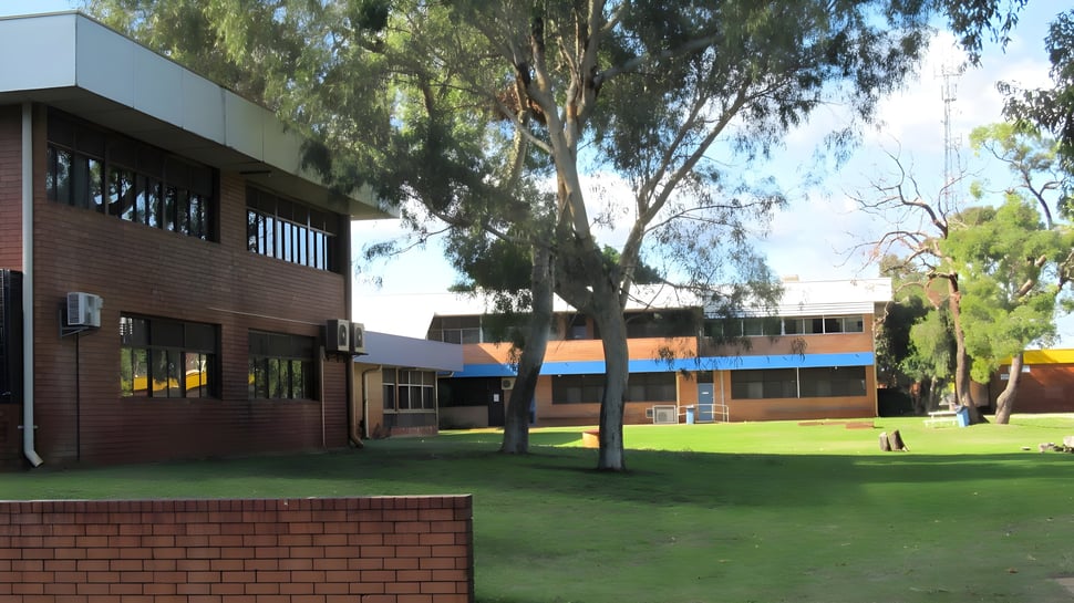 El moderno edificio de ladrillo con acentos de color en el campus del Kiara College está rodeado de un área verde y árboles.