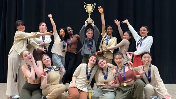 Las estudiantes de Kildonan East Collegiate celebran en el escenario y sostienen un trofeo durante la ceremonia de premiación.